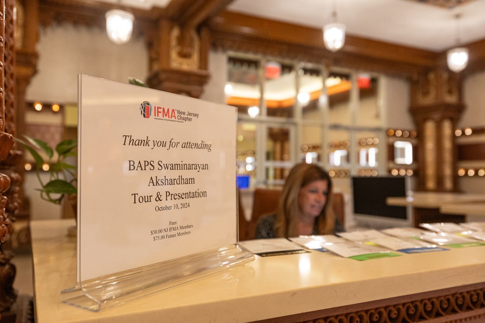 A woman is sitting at a counter with a sign on it.