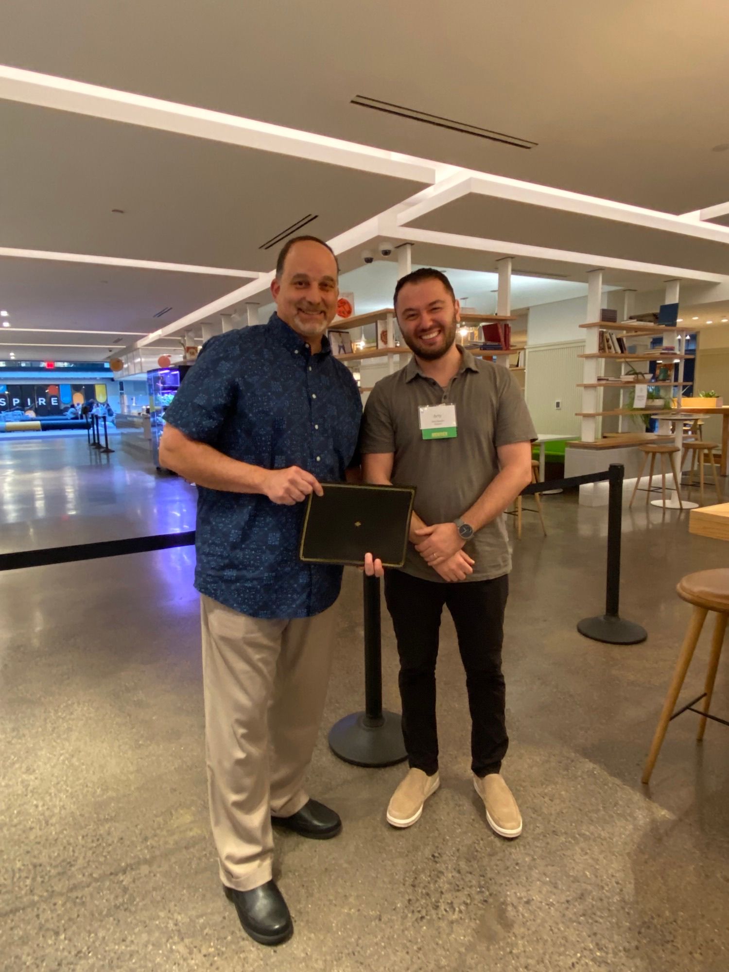 Two men are standing next to each other in a room holding a tablet.
