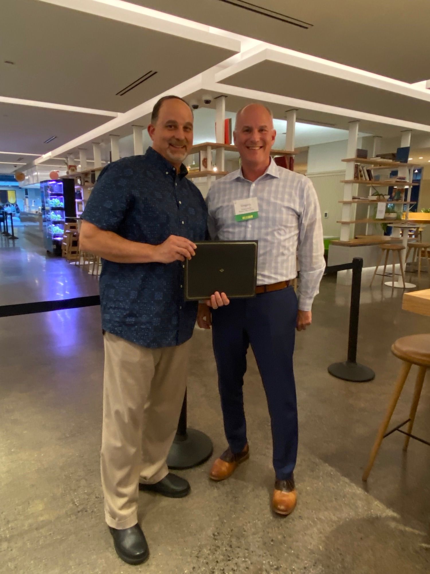 Two men are standing next to each other holding a laptop