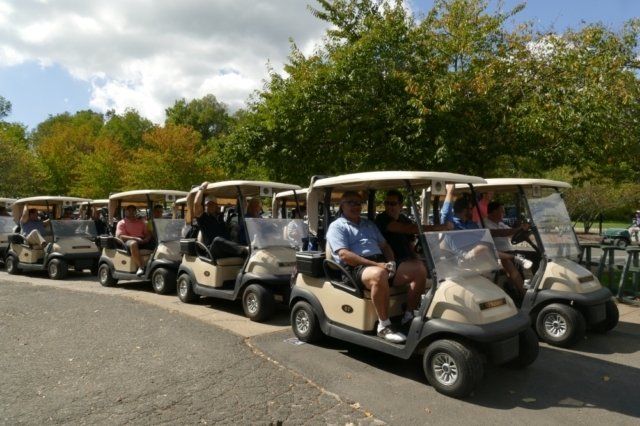 A row of golf carts are parked in a parking lot