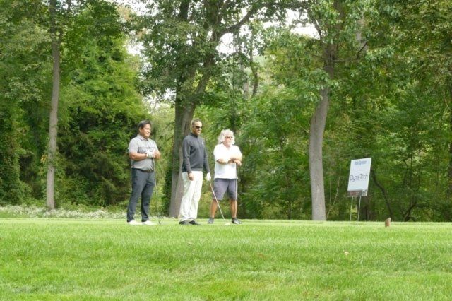 A group of people standing on top of a lush green golf course.