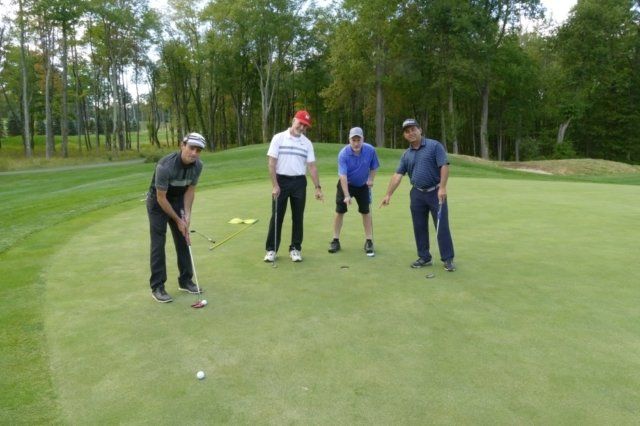 A group of men are playing golf on a green.