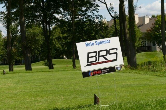 A hole sponsor brs sign is in the middle of a golf course