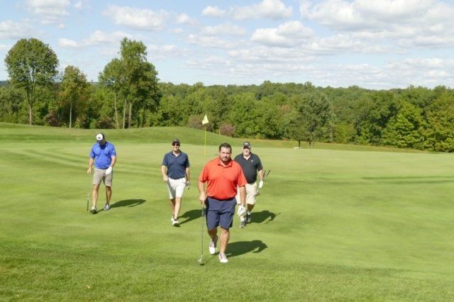 A group of men are walking on a golf course.