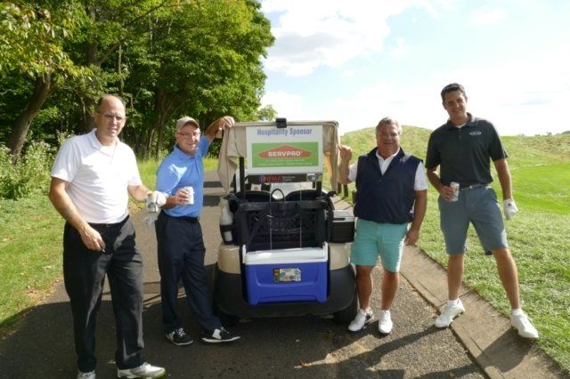 A group of men are standing in front of a golf cart