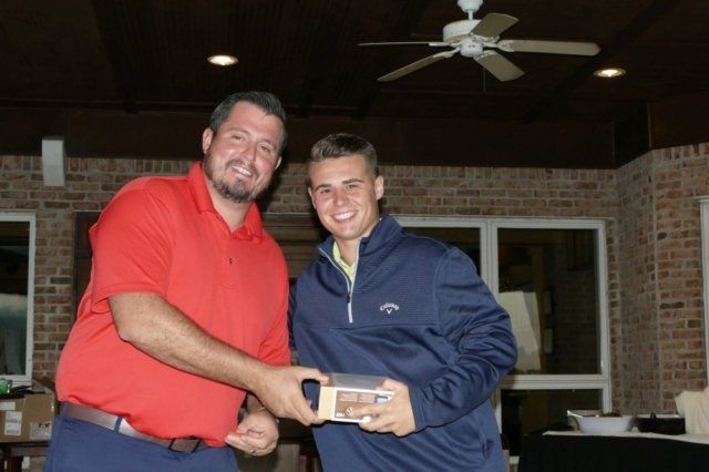 A man in a red shirt is shaking hands with another man in a blue jacket
