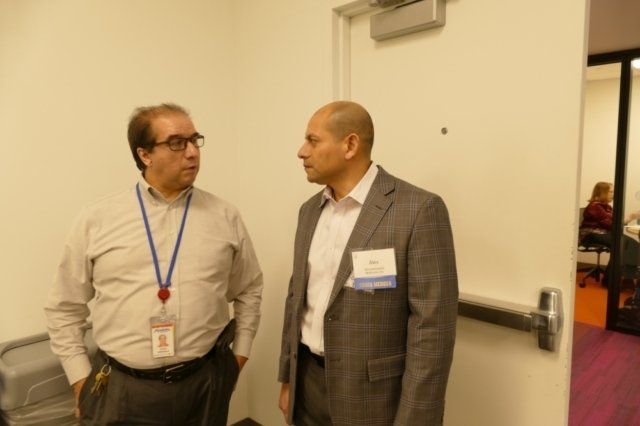 Two men standing next to each other in a room talking