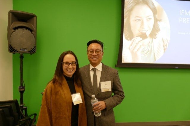 A man and a woman are posing for a picture in front of a green screen.