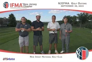 Four men are standing on a golf course holding golf clubs