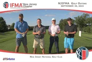 Four men are standing on a golf course holding golf clubs