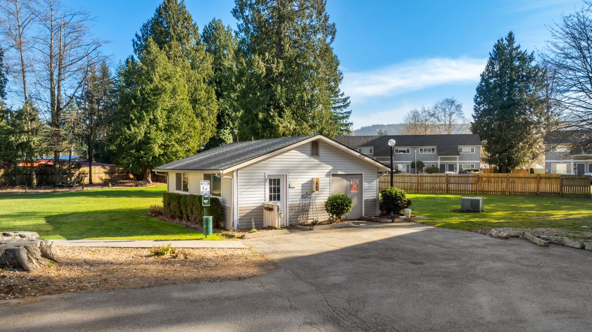 A small white house is sitting in the middle of a lush green field.