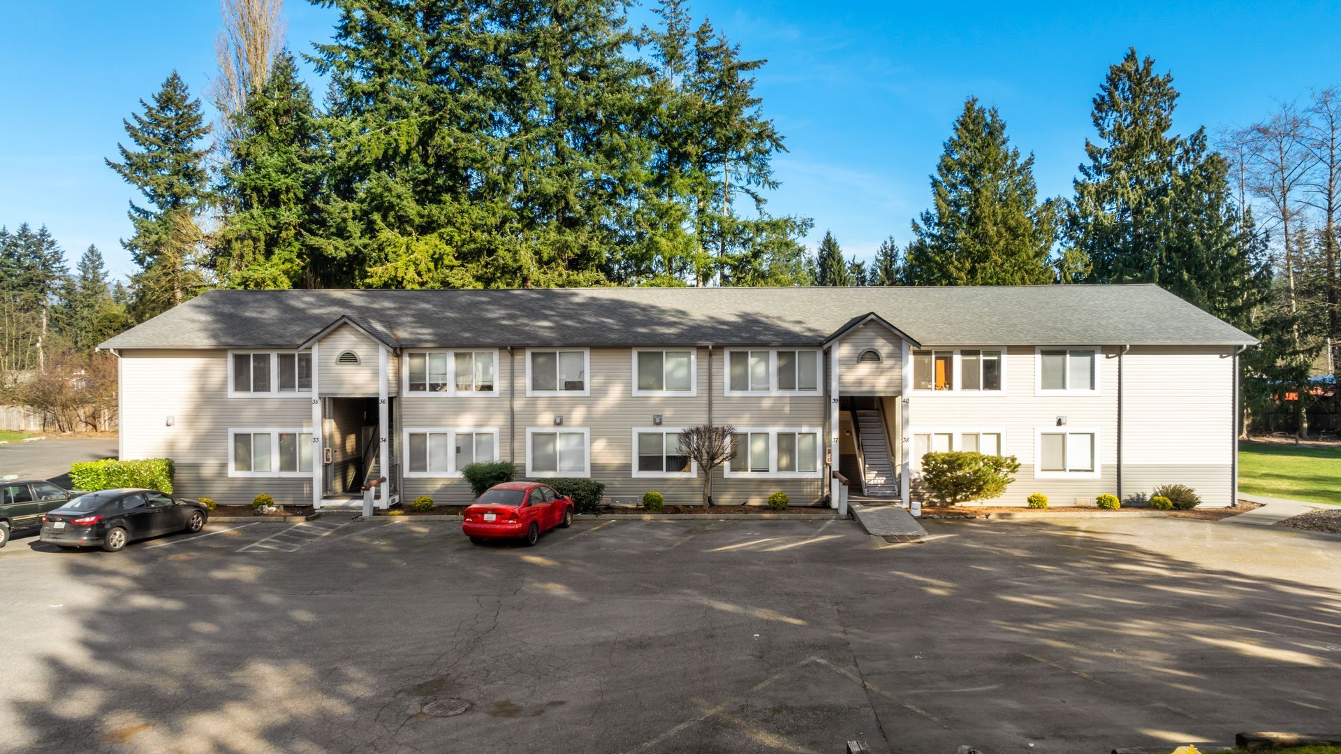 A large apartment building with a lot of cars parked in front of it.