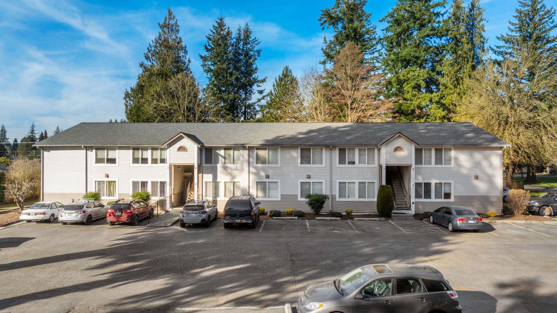 A large apartment building with cars parked in front of it.
