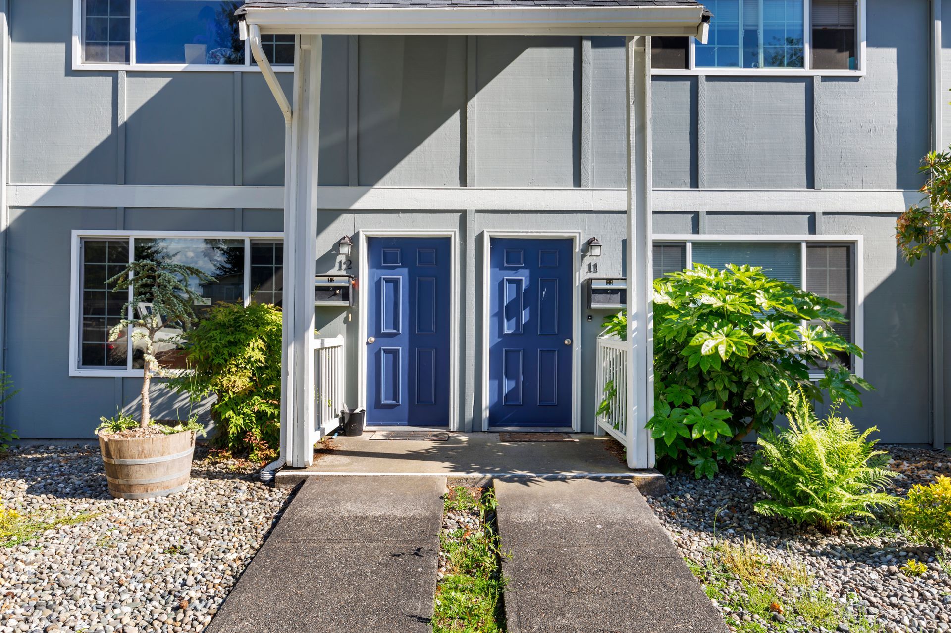The front of a house with blue doors and a walkway leading to it.