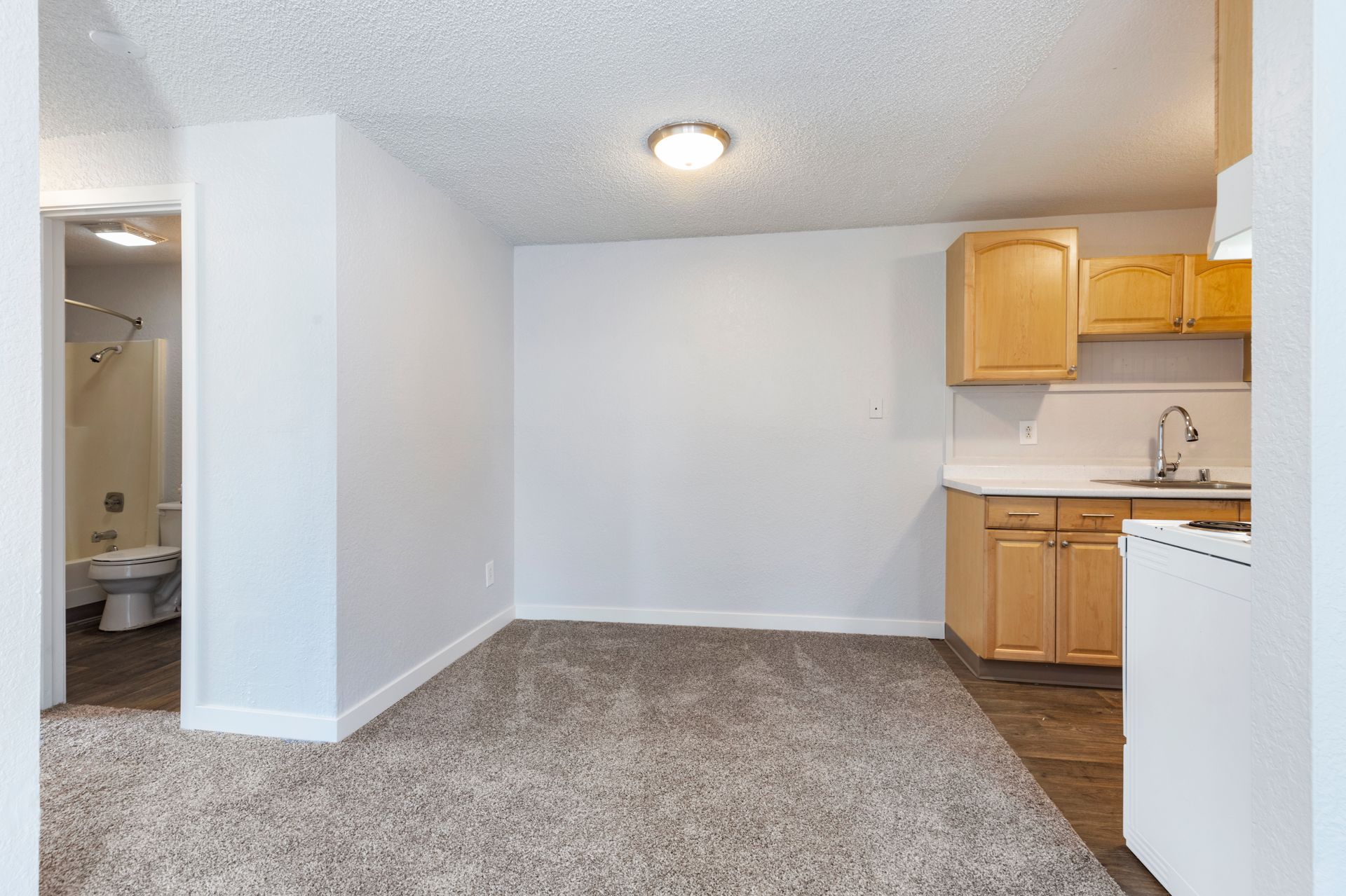 An empty room with a kitchen and a bathroom