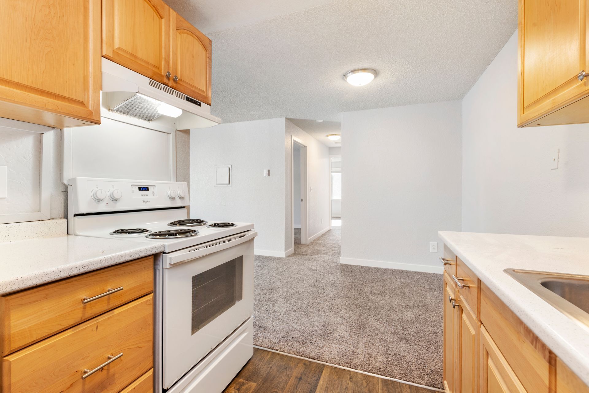 A kitchen with wooden cabinets , a stove , and a sink.