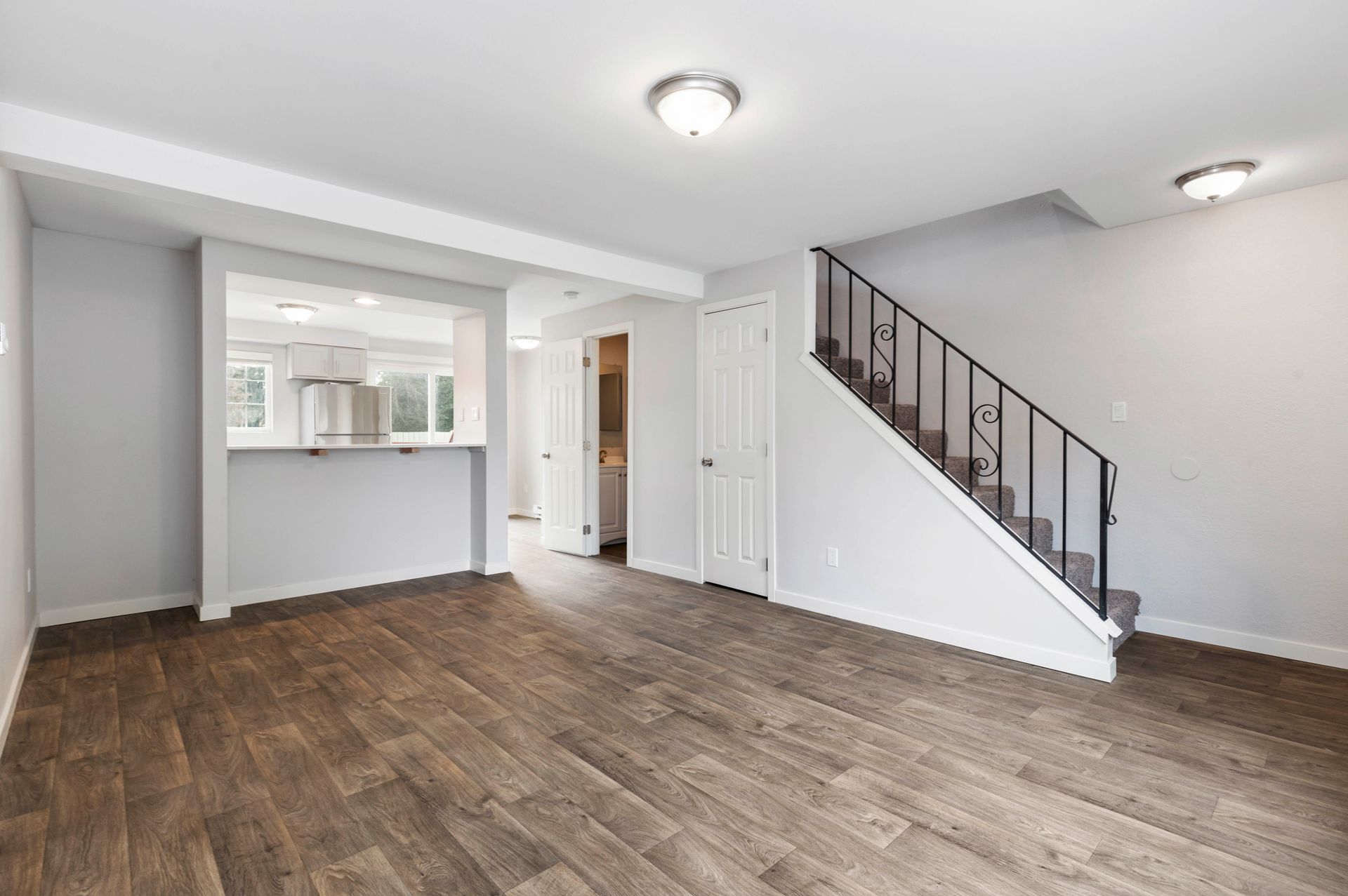 An empty living room with hardwood floors and stairs leading up to the second floor.