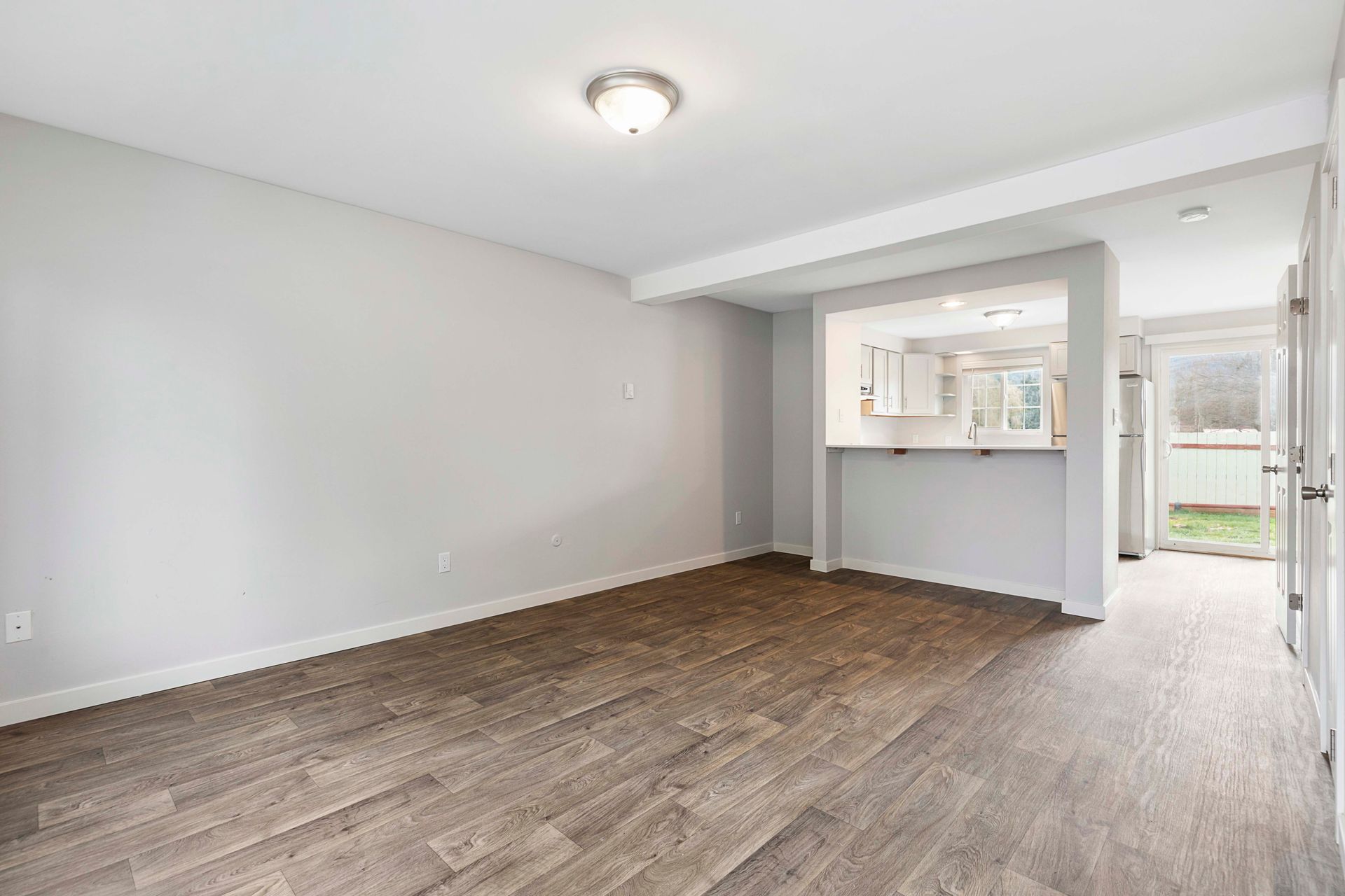 An empty living room with hardwood floors and white walls.