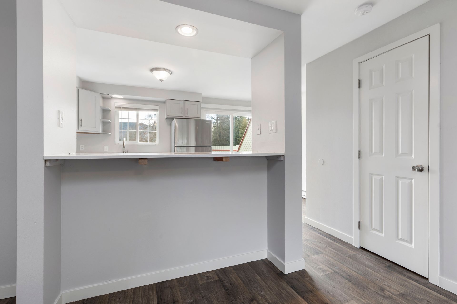 There is a kitchen in the background and a hallway in the foreground.