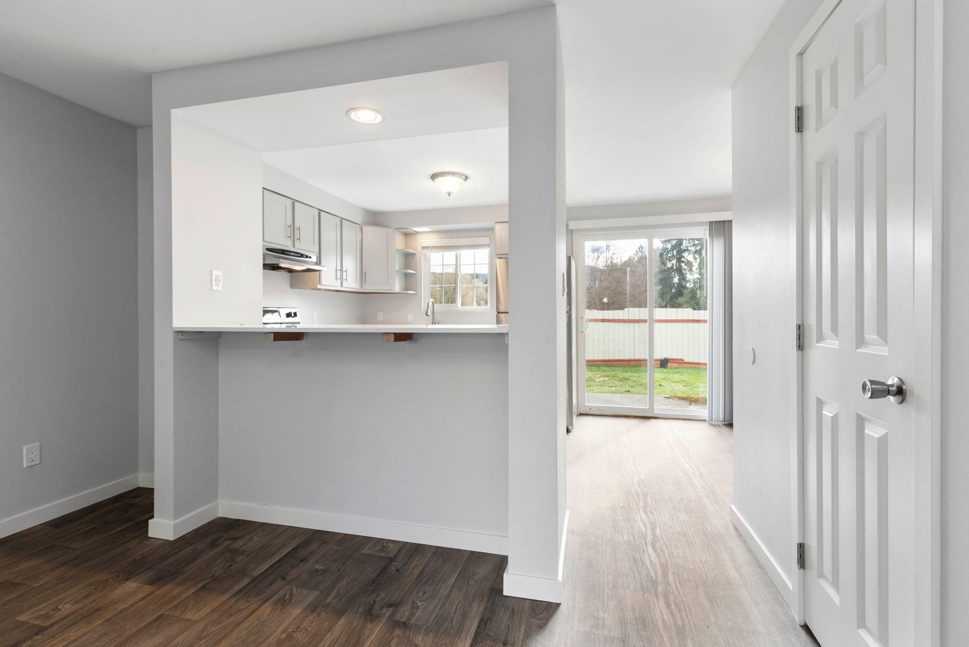 There is a sliding glass door between the kitchen and the living room.