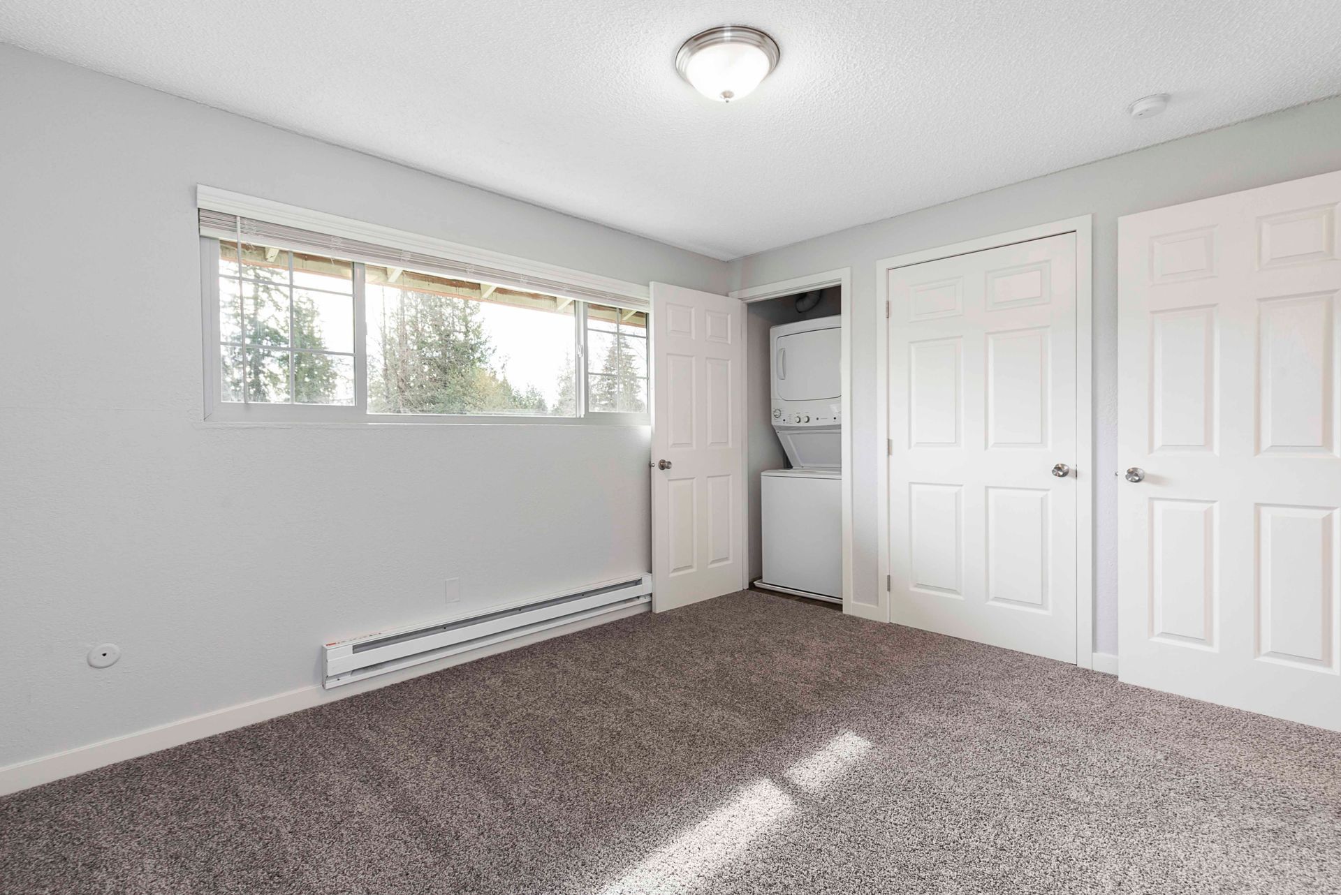 An empty bedroom with a washer and dryer in the closet.