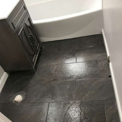 Dark tiled bathroom floor, vanity, and tub.