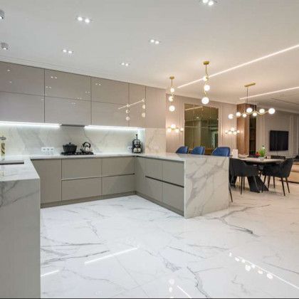 Modern, open-concept kitchen with marble countertops and flooring, light gray cabinets, and pendant lighting.
