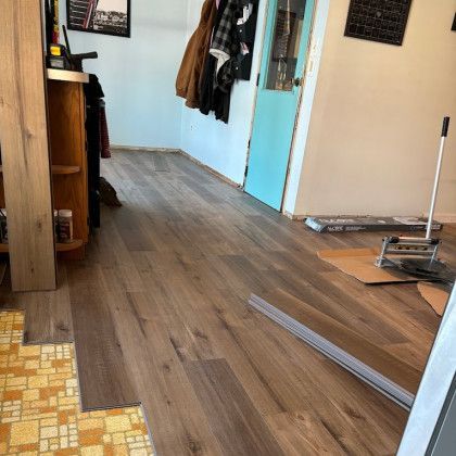 Laying new wooden flooring over existing yellow and orange tile; room interior.