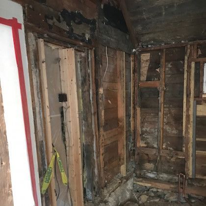 Room interior with exposed wooden framing and wall. Shows signs of renovation or damage.