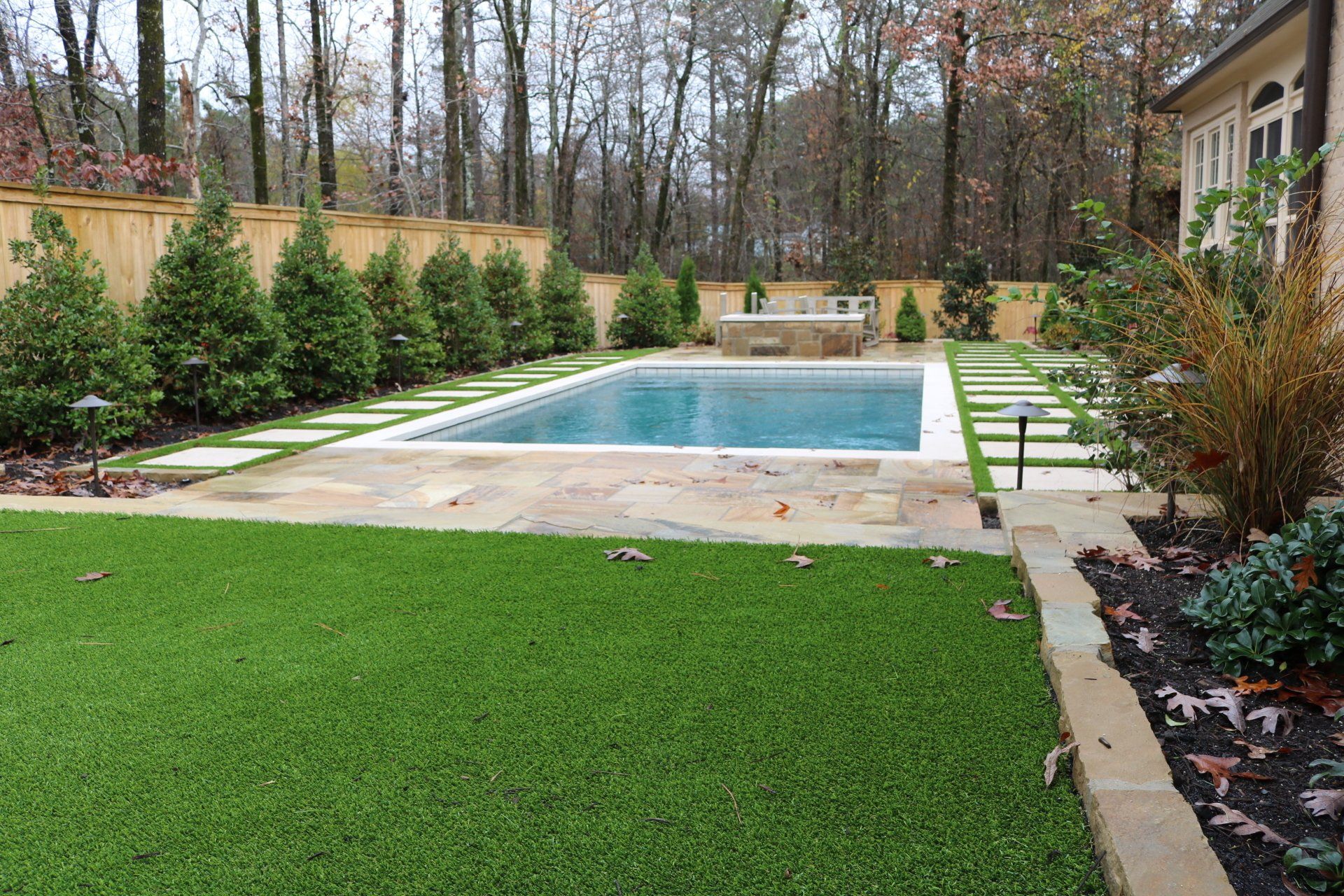 There is a large swimming pool in the backyard of a house.