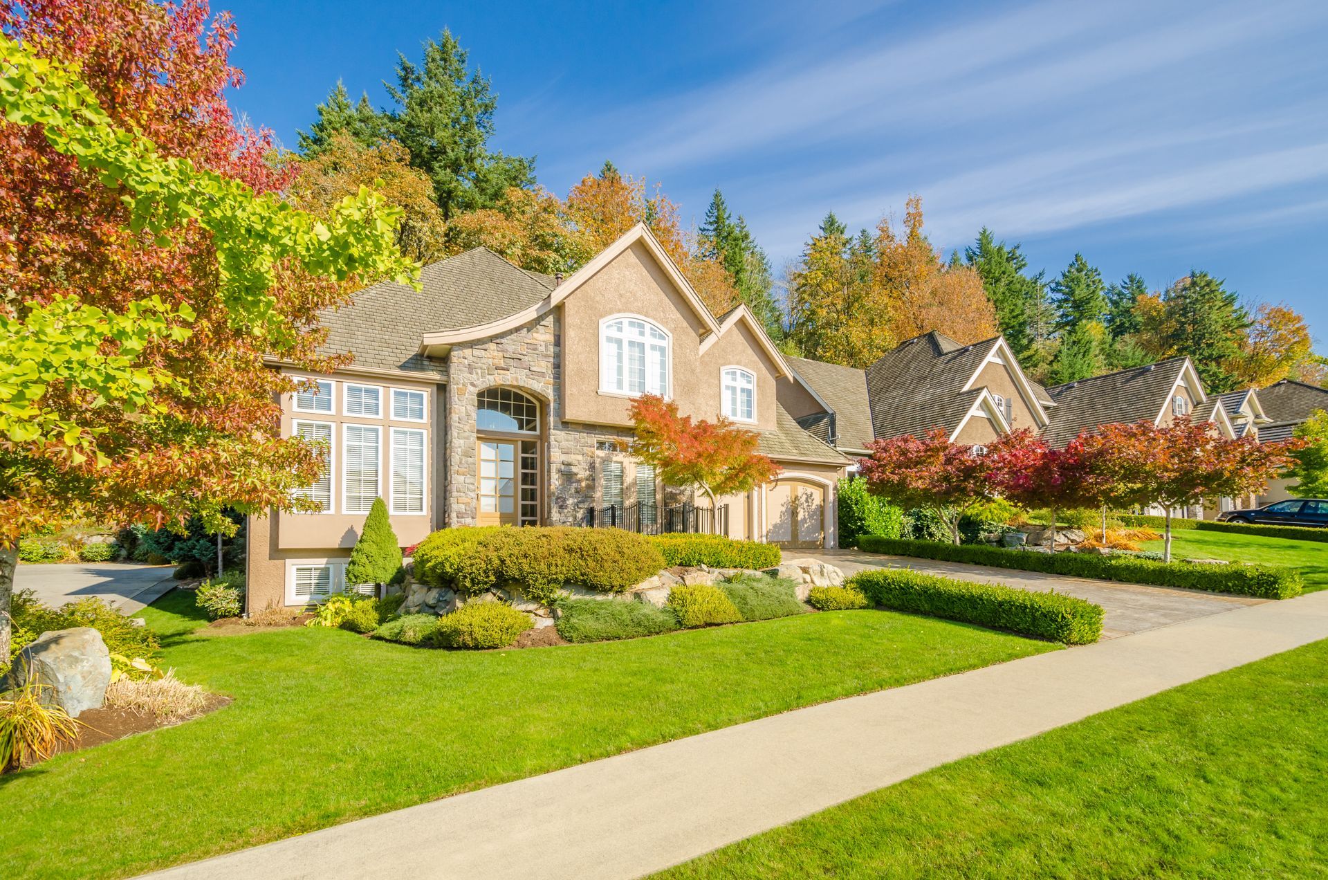 A large house with a lush green lawn and trees in front of it.