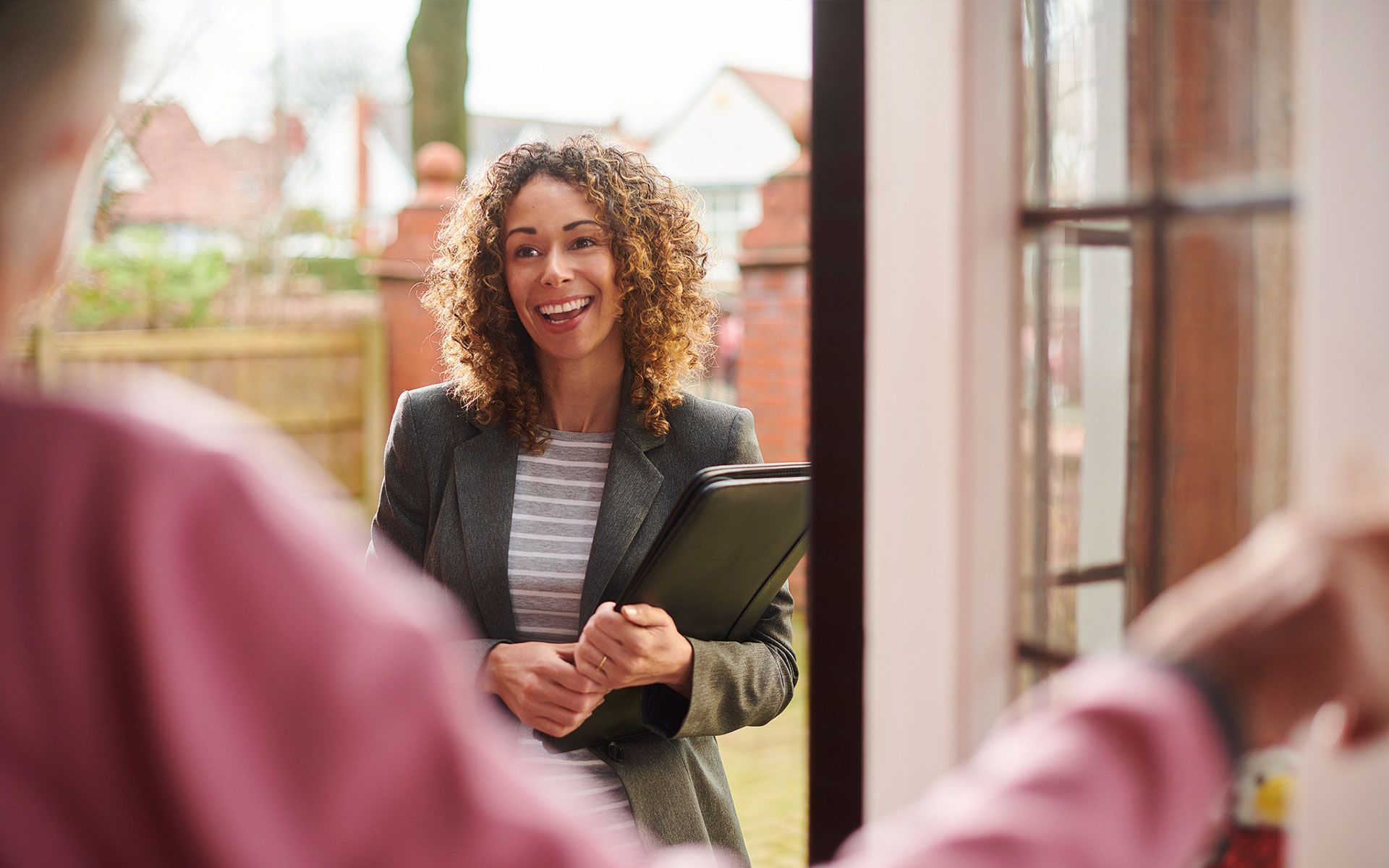 A woman is standing in front of a door talking to a man.