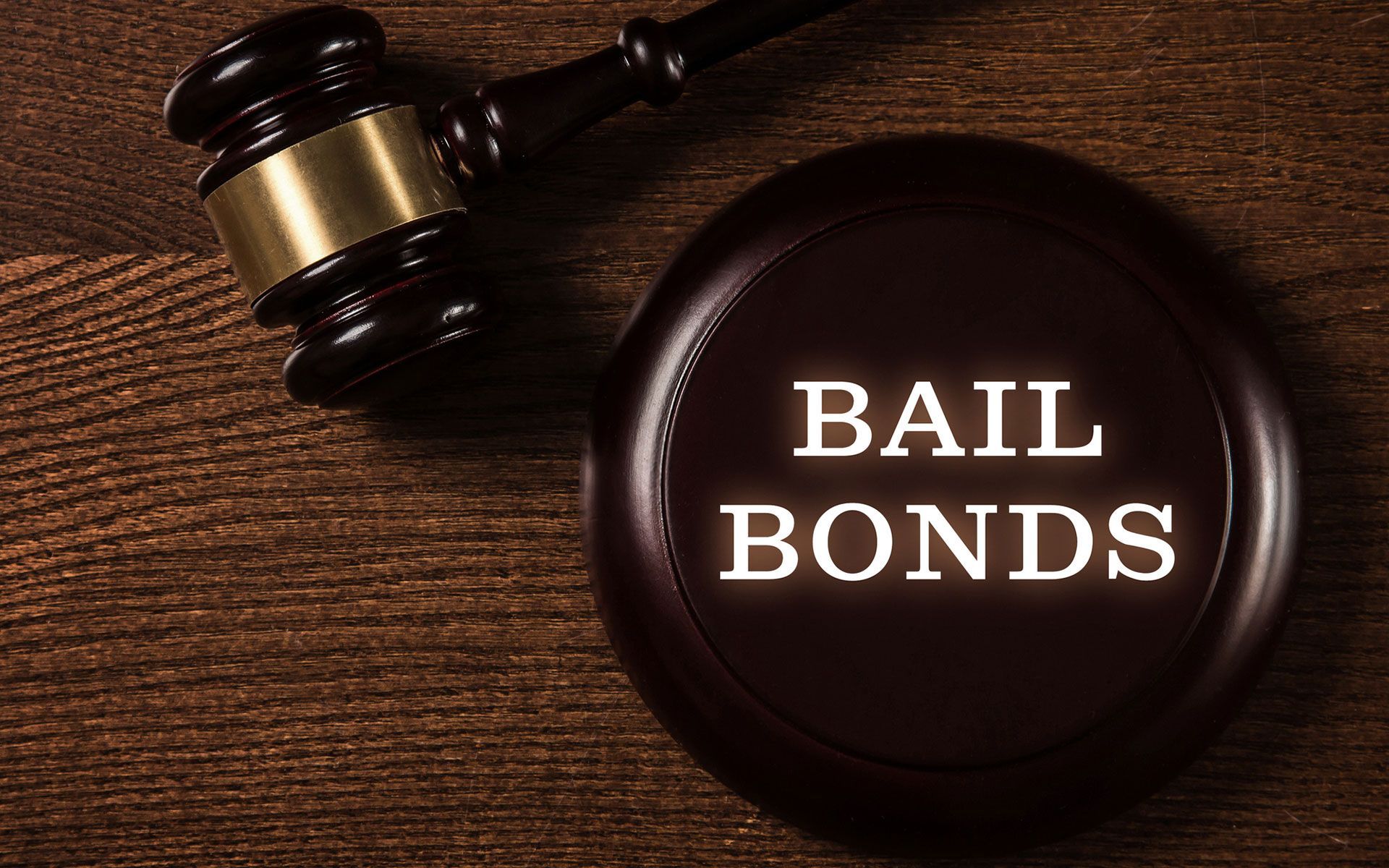 A judge 's gavel and a bail bonds sign on a wooden table.