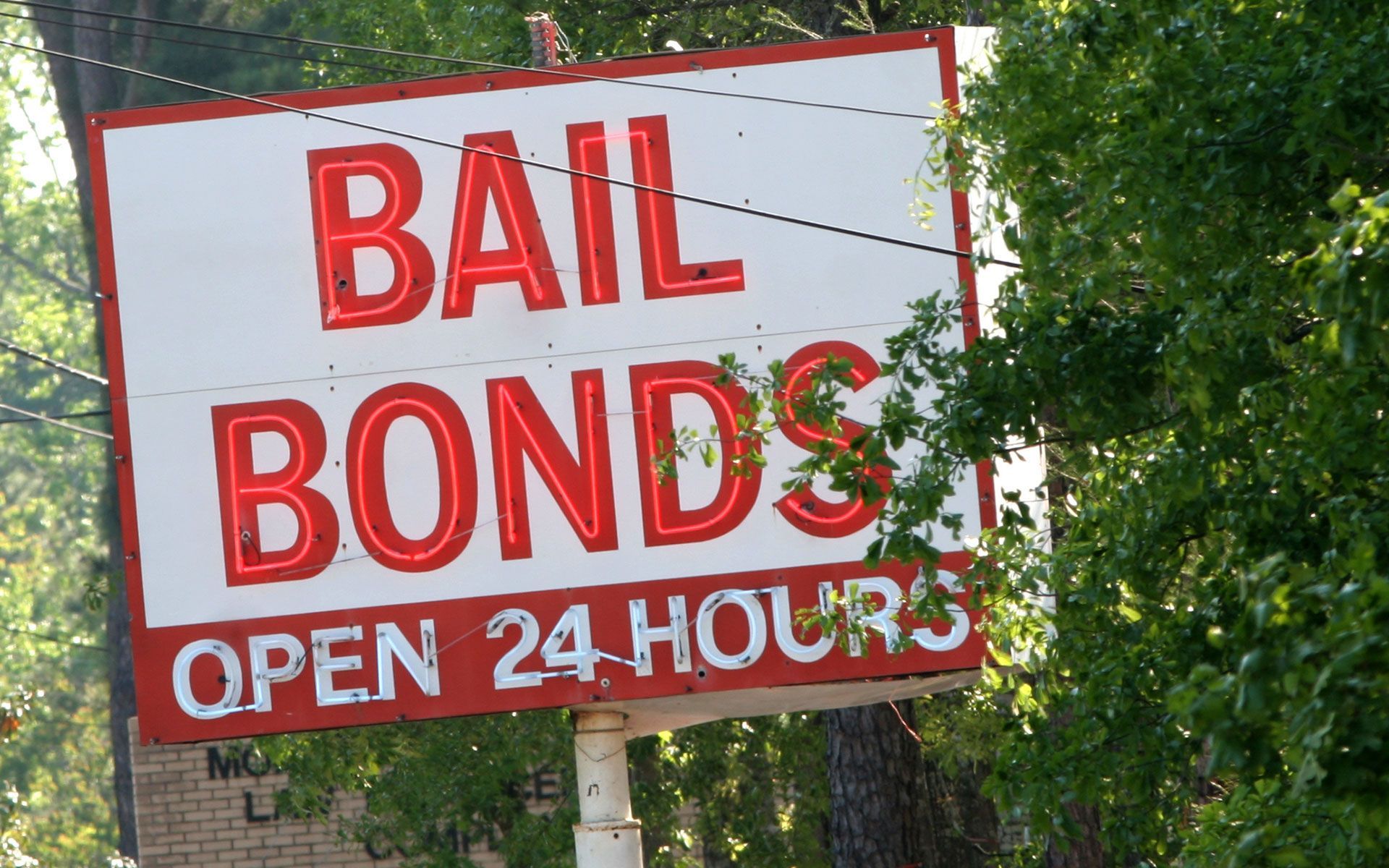 A red and white sign that says bail bonds open 24 hours