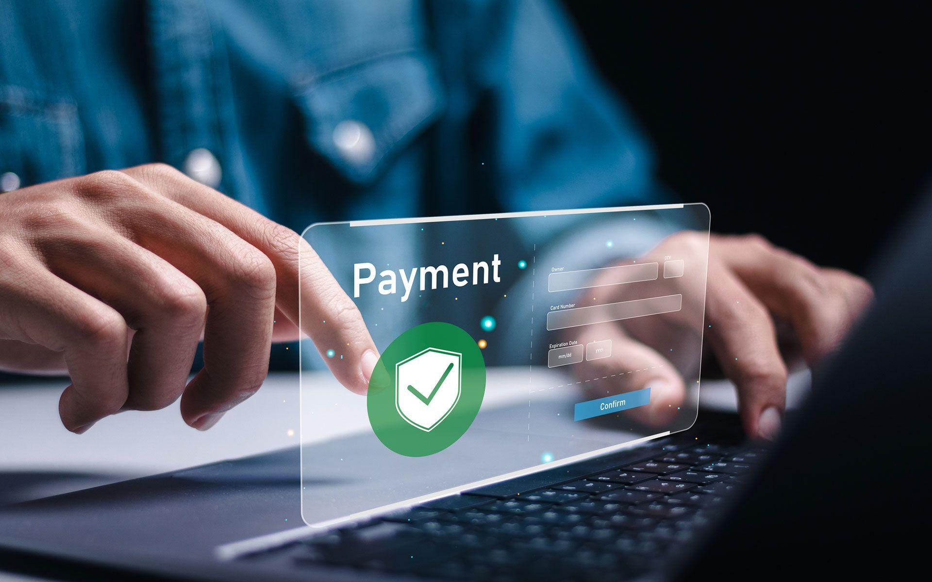 A person is holding a credit card in front of a laptop computer.