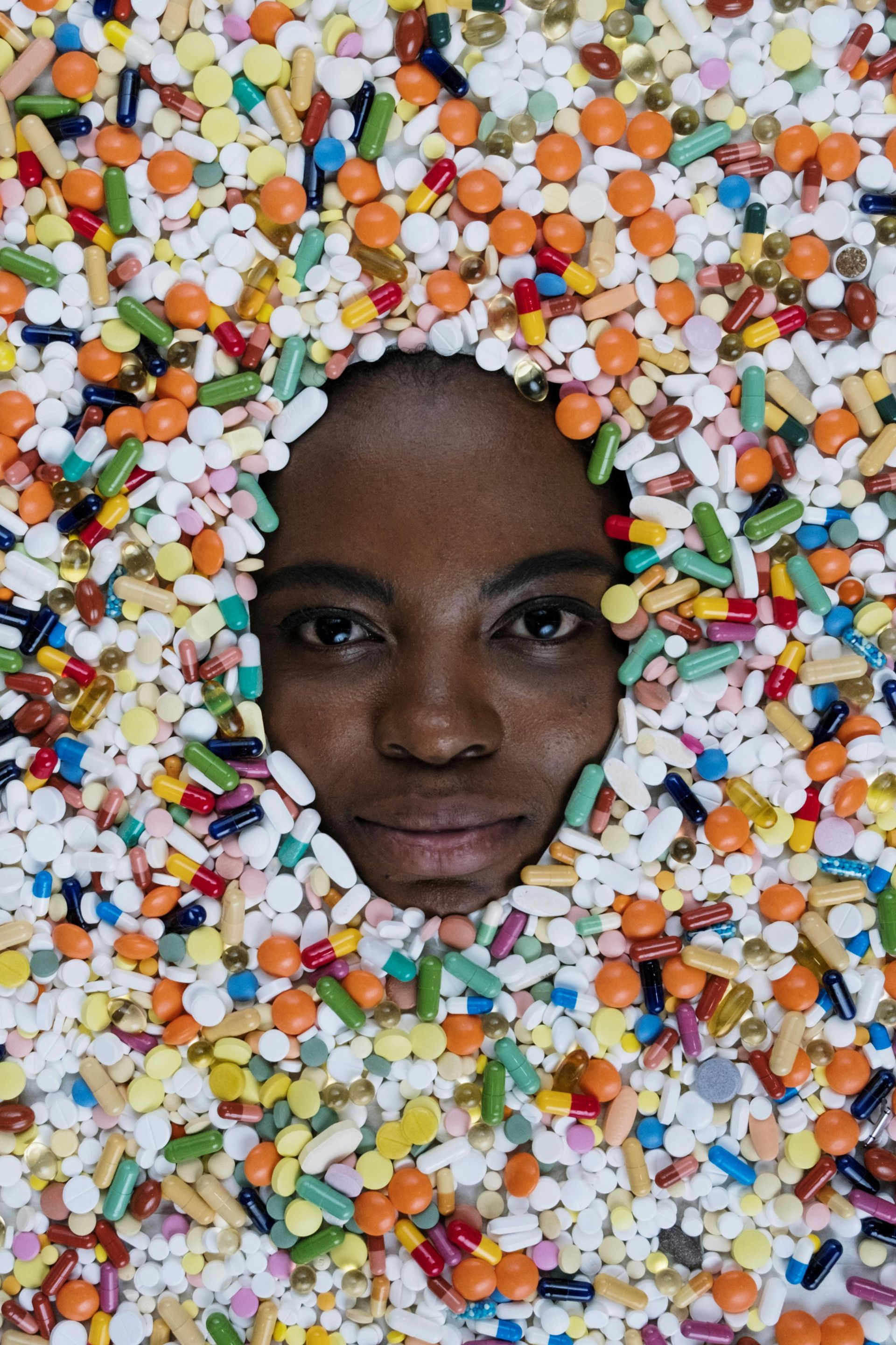 A woman 's face is surrounded by pills and sprinkles.