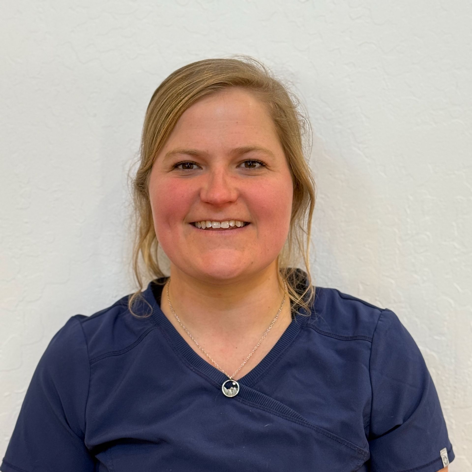 a young woman with purple hair is wearing a green scrub top and a black jacket .