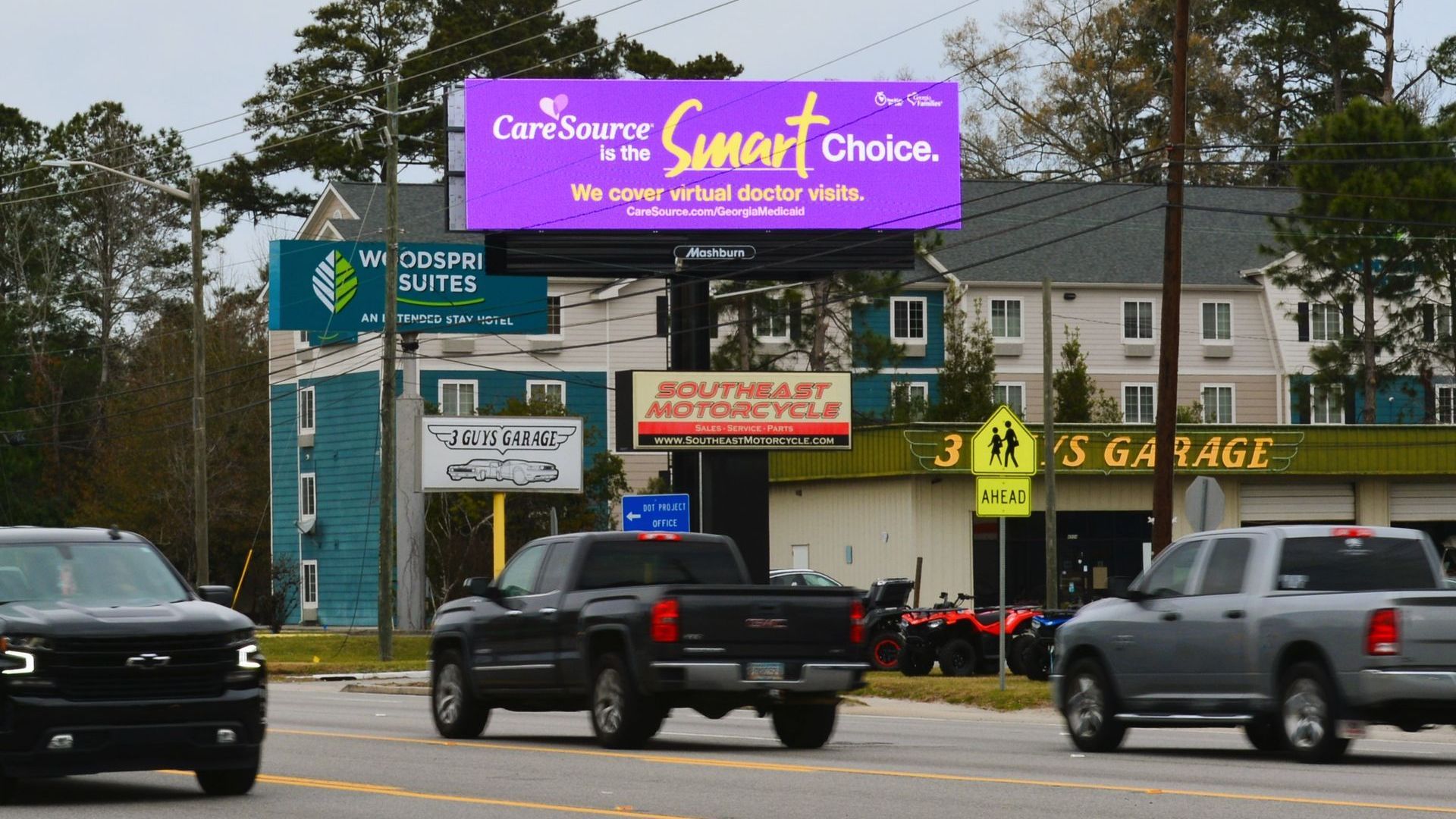 cars are driving down a street in front of a billboard that says smart choice