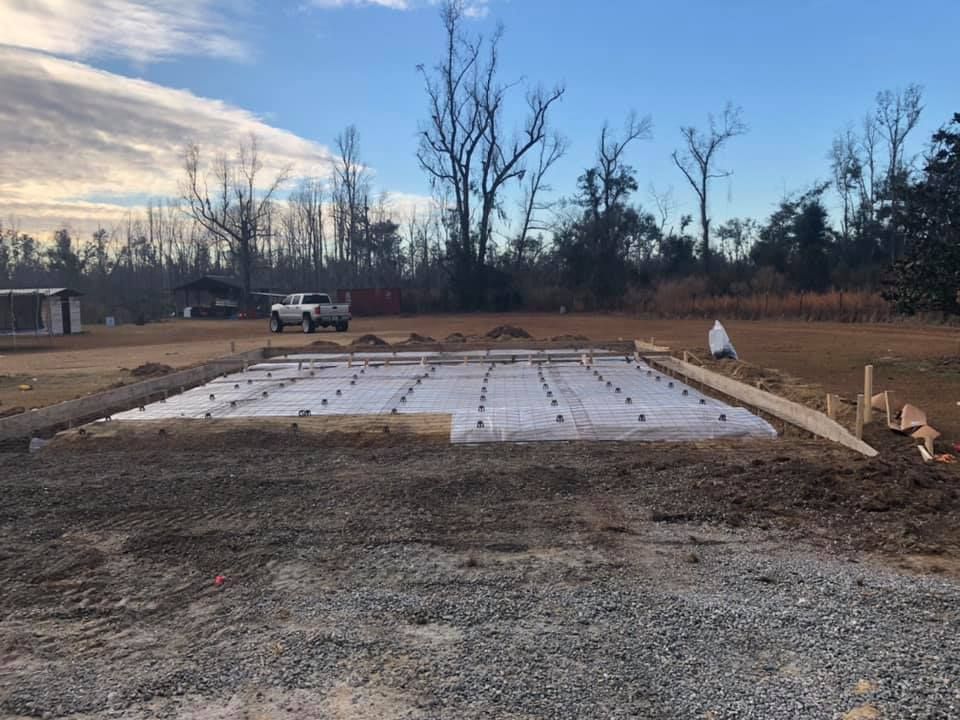 Concrete slab foundation framed with wood, prepared for construction, with a truck in the background.
