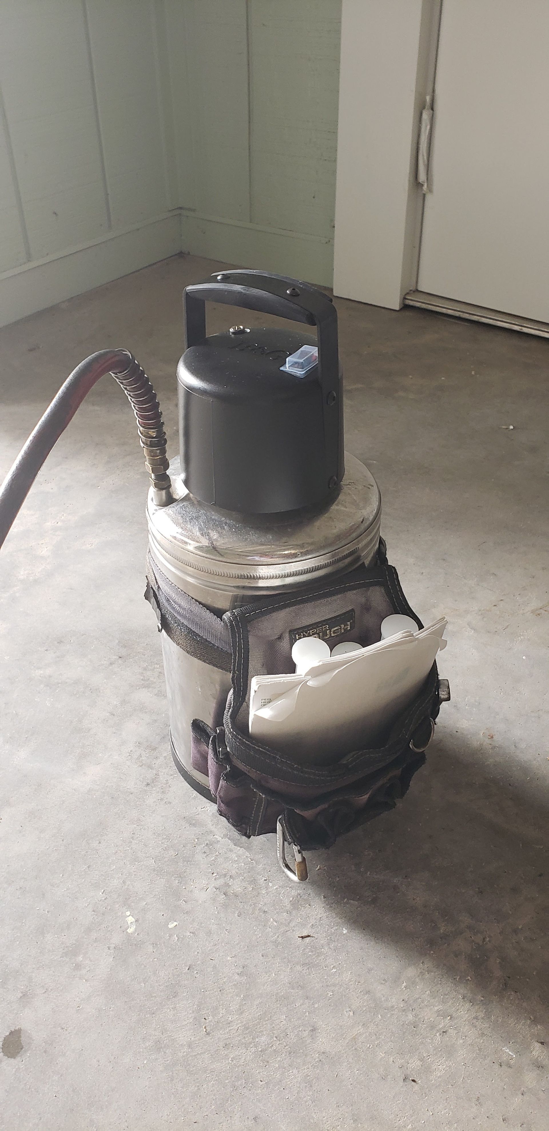 A damaged vacuum cleaner in a room with a concrete floor and white door.