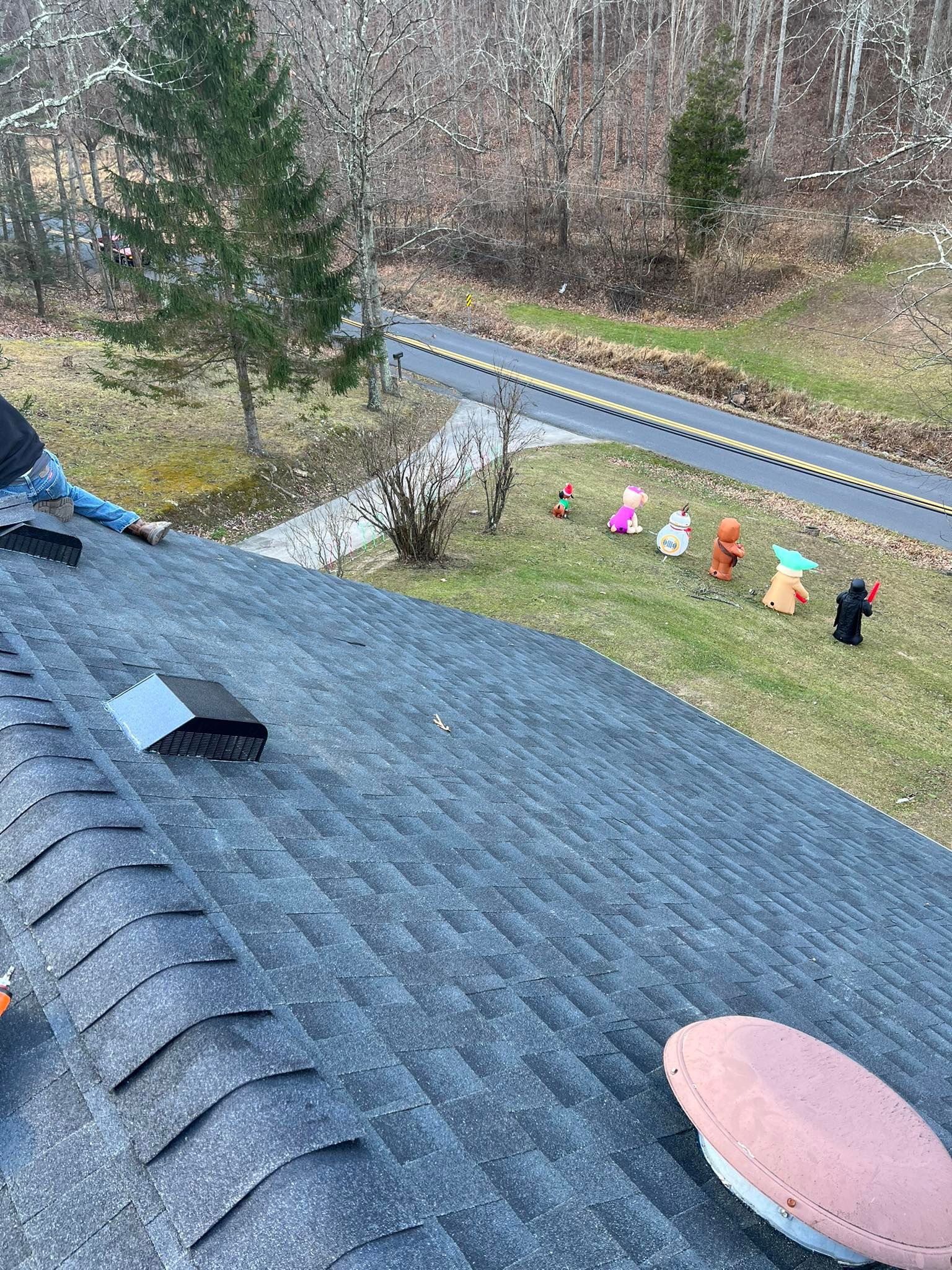 A group of stuffed animals are sitting on the roof of a house.