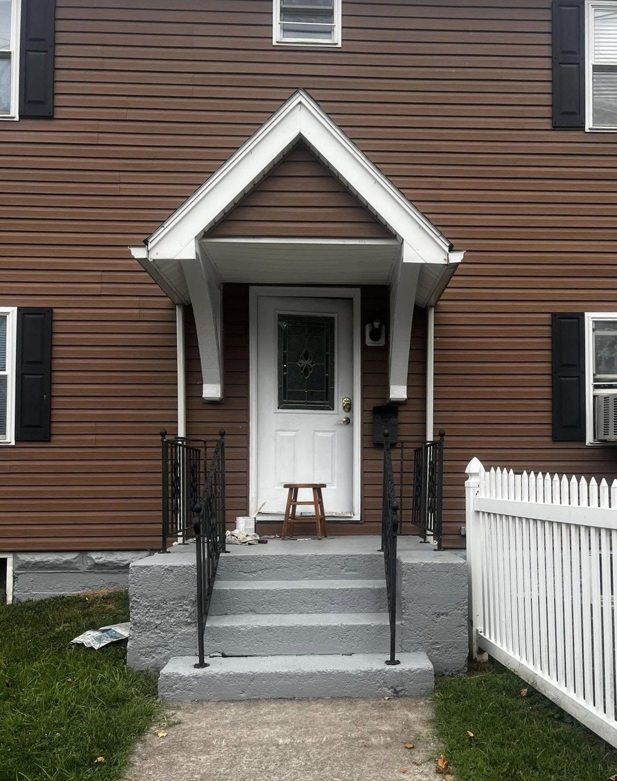 A brown house with a white door and a white picket fence