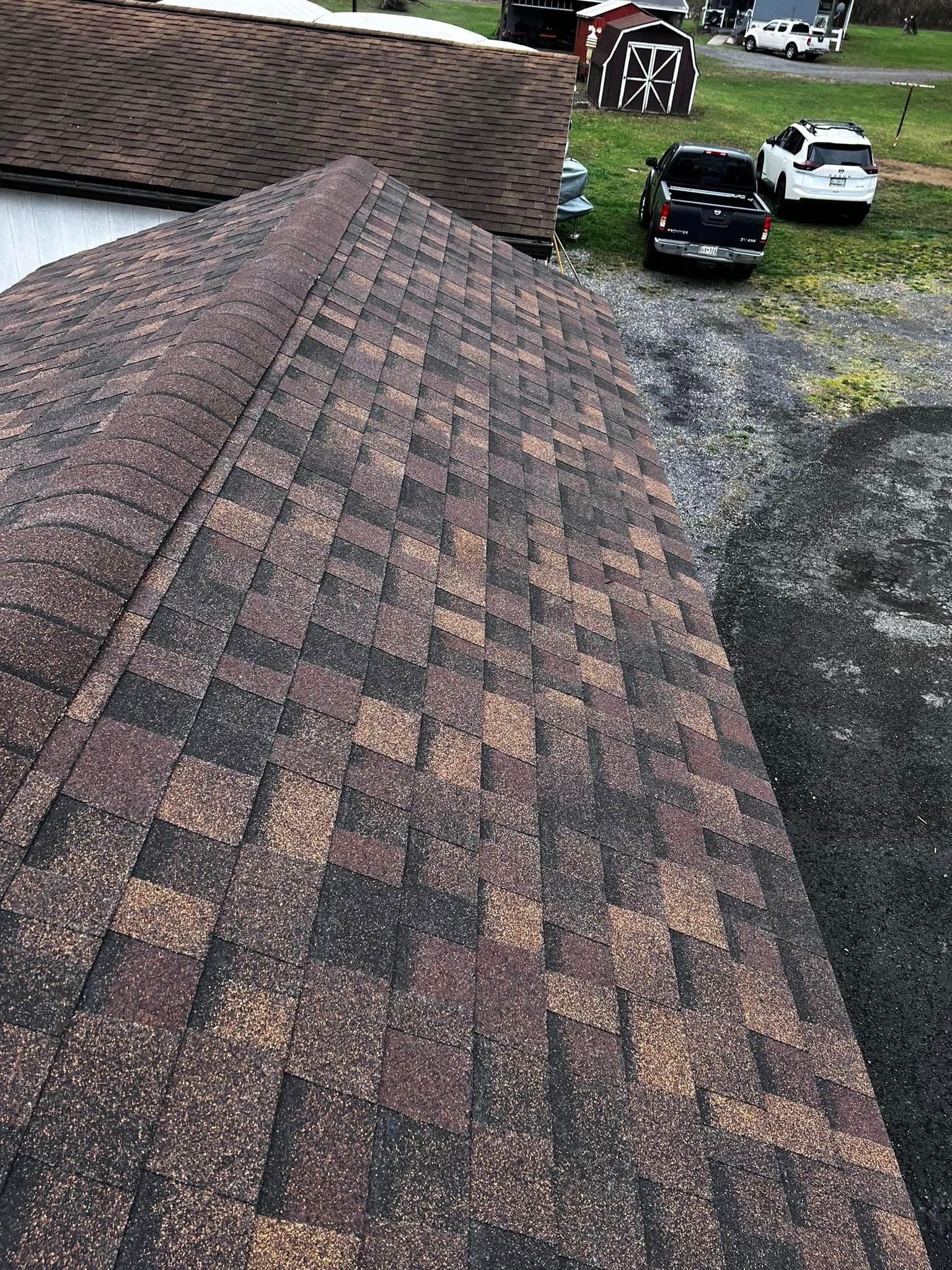 A roof with a truck parked on it and a barn in the background.