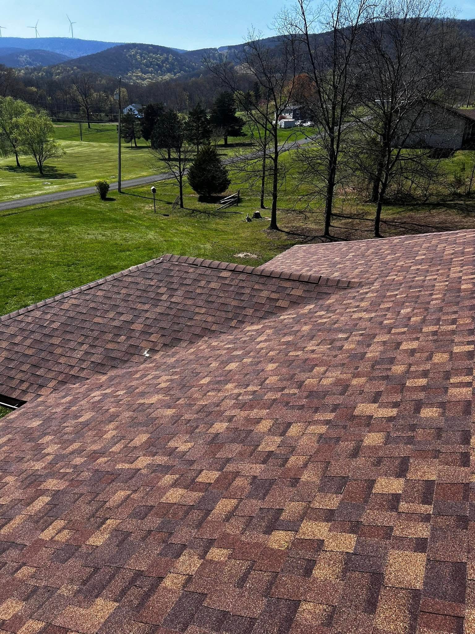 A roof with a view of a field and mountains in the background.