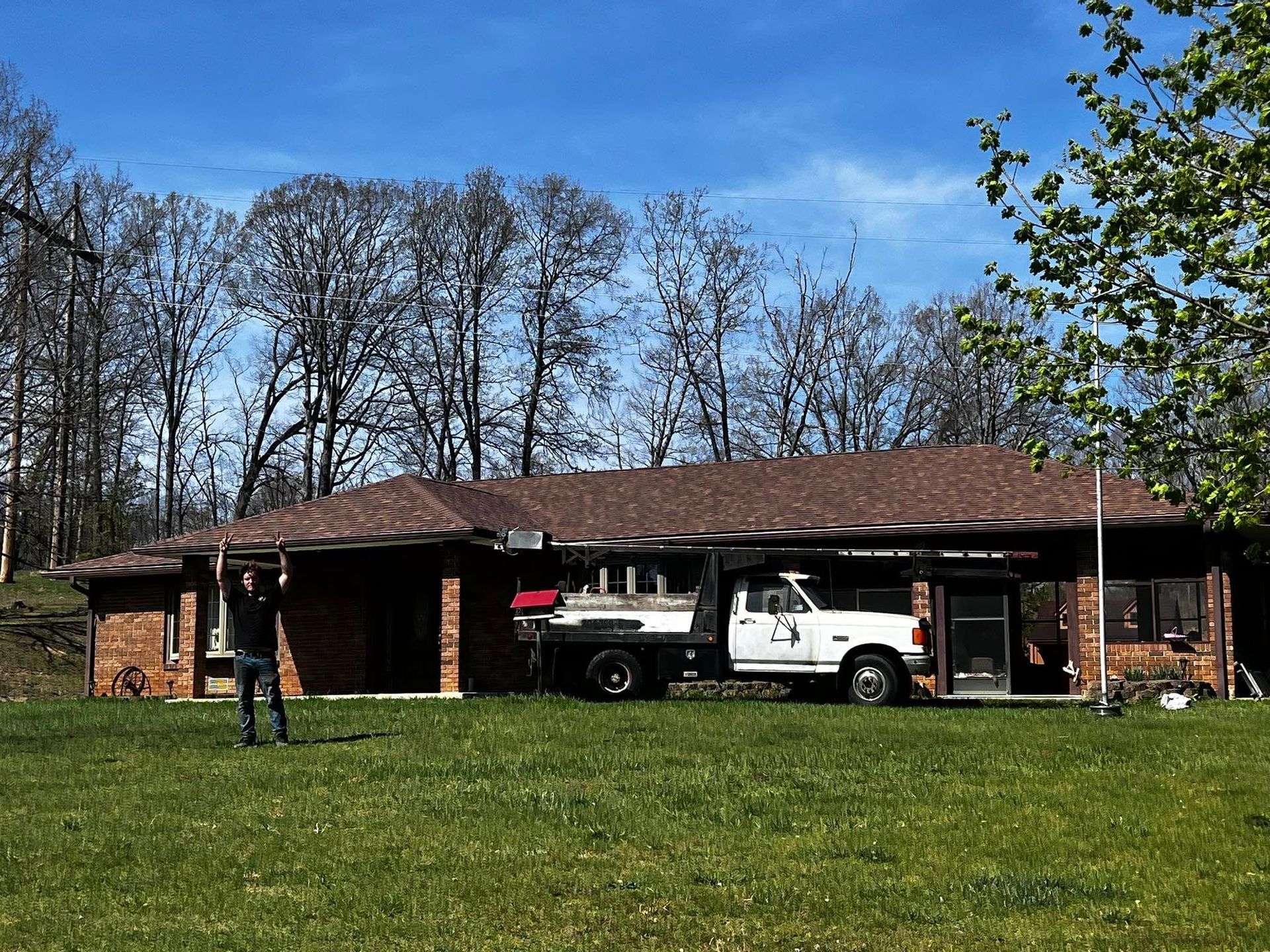 A white truck is parked in front of a brick house.