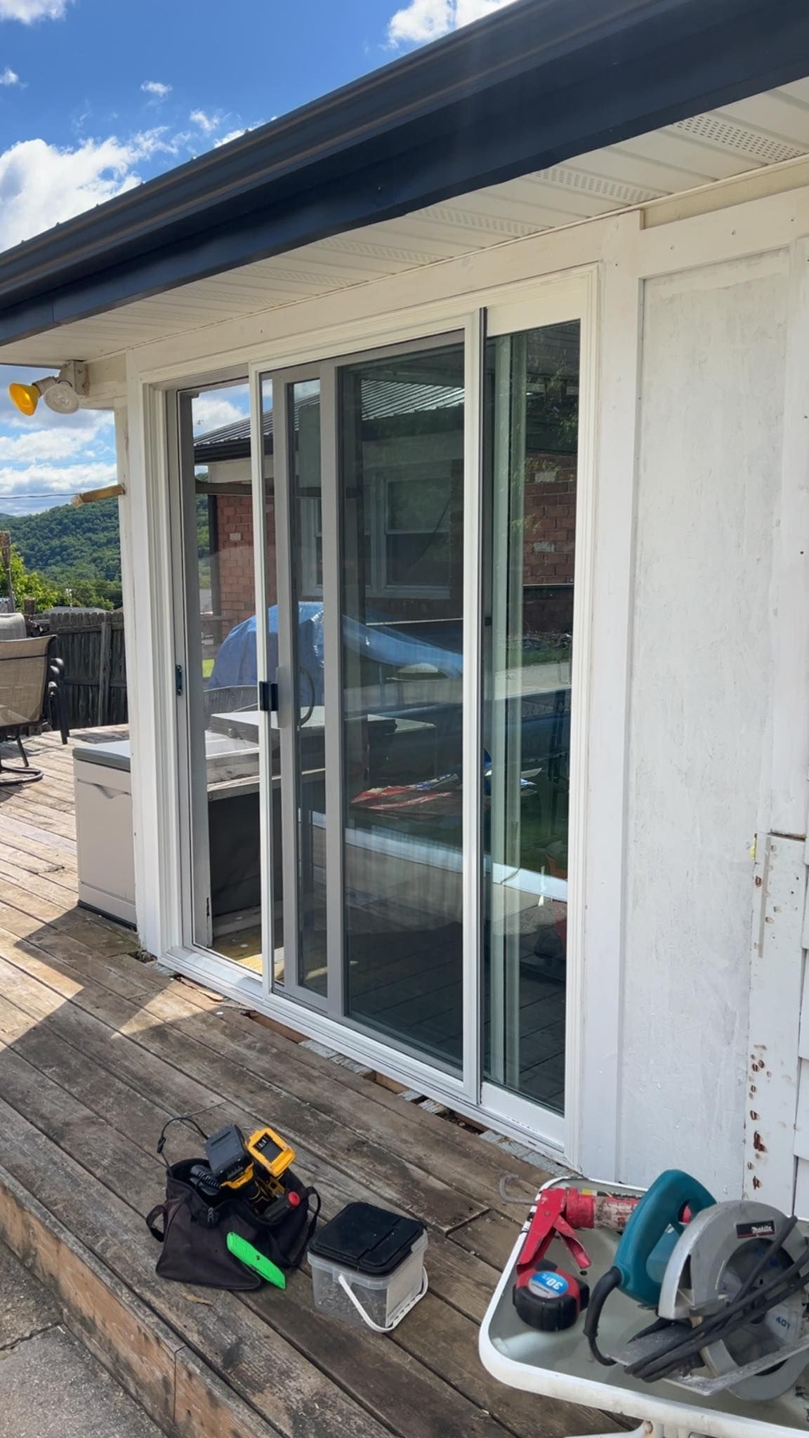 A sliding glass door is being installed on the side of a house.
