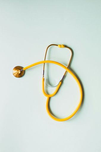 Yellow stethoscope on a light blue background, angled from upper right to lower left.