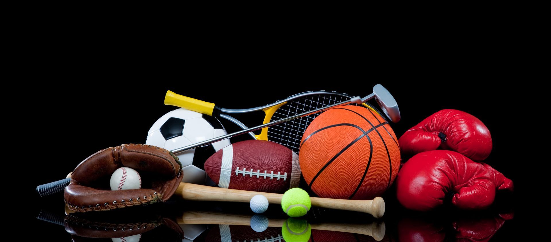 A collection of various sports equipment including a basketball, football, boxing gloves, and balls on a black background.