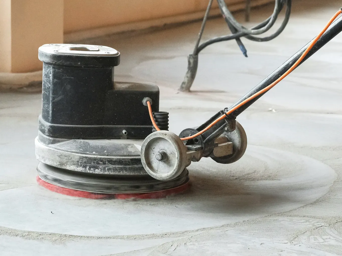 Close-up of a small black electric motor with wires on a dusty floor