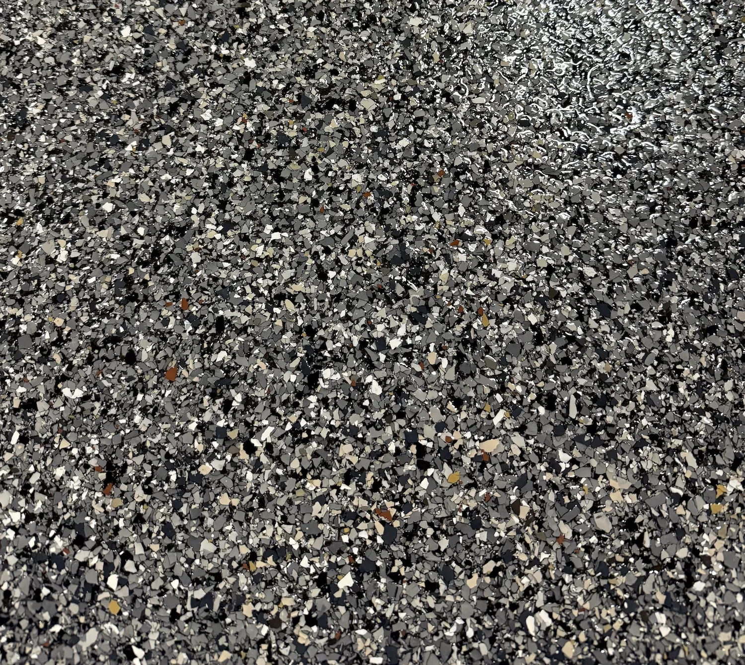 Close-up of a gravel surface with gray, black, and tan stones
